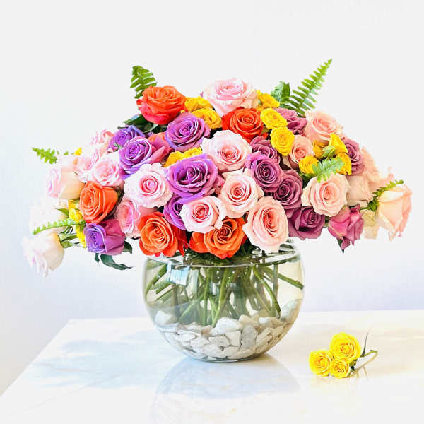 Colorful rose bouquet in a round glass vase with white stones