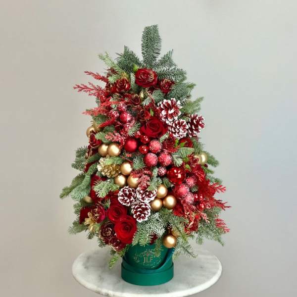 Red roses and pinecones arranged in a green container