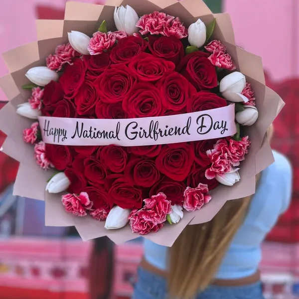 Bouquet of red roses, pink carnations, and white tulips with a ribbon