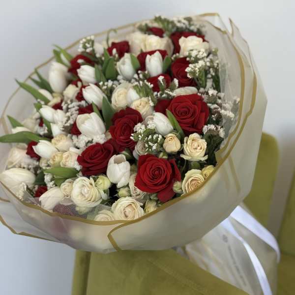 Bouquet of red and white roses with white tulips wrapped in sheer paper