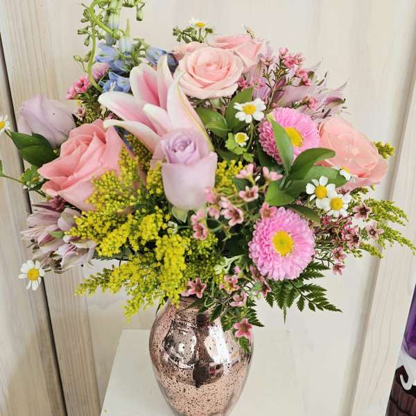 Mixed pink and pastel flowers arranged in a metallic vase