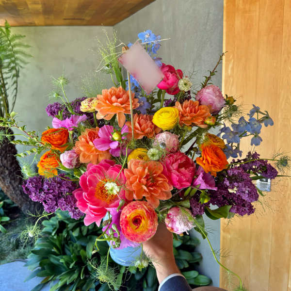 Colorful mixed bouquet in a vase with pink, orange, yellow, purple, and blue flowers