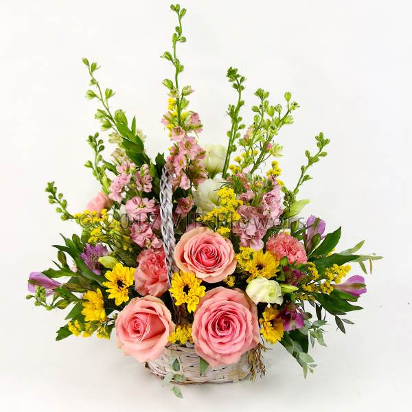 Basket arrangement with pink roses, yellow flowers, and tall pink blooms