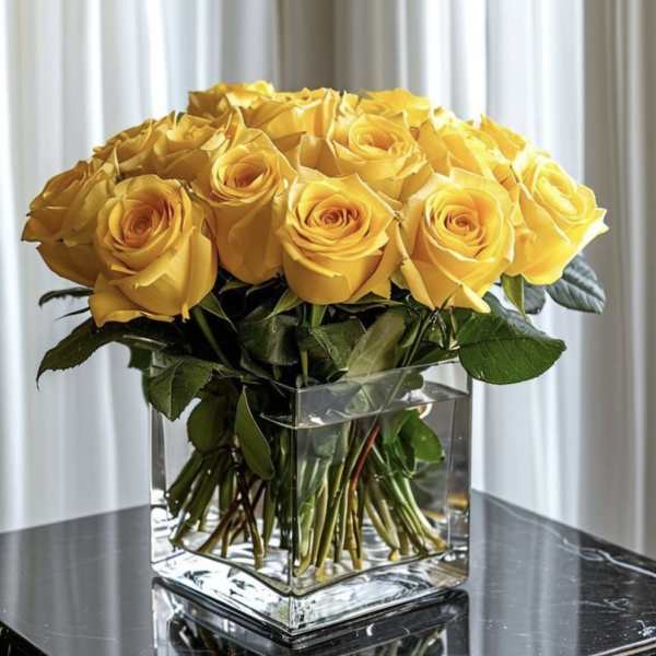 Yellow roses arranged in a clear square glass vase