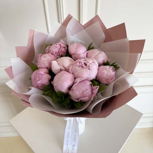 Bouquet of pink peonies wrapped in layered pink and white paper