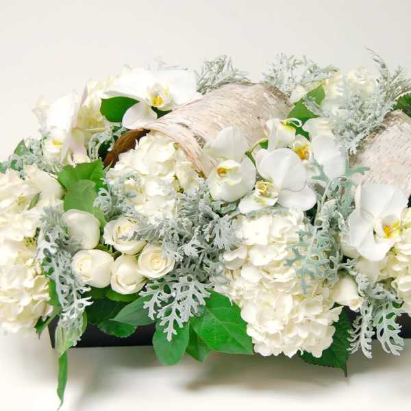 White floral arrangement with orchids and hydrangeas in a low container