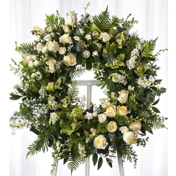 Large white floral wreath with roses and greenery on an easel