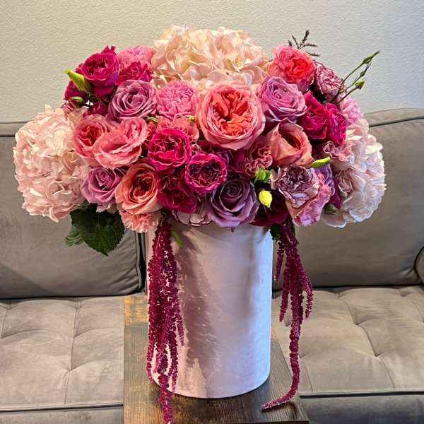 Large pink and purple floral arrangement in a white vase