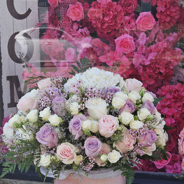 Large bouquet of pink, white, and lavender roses in a pink vase