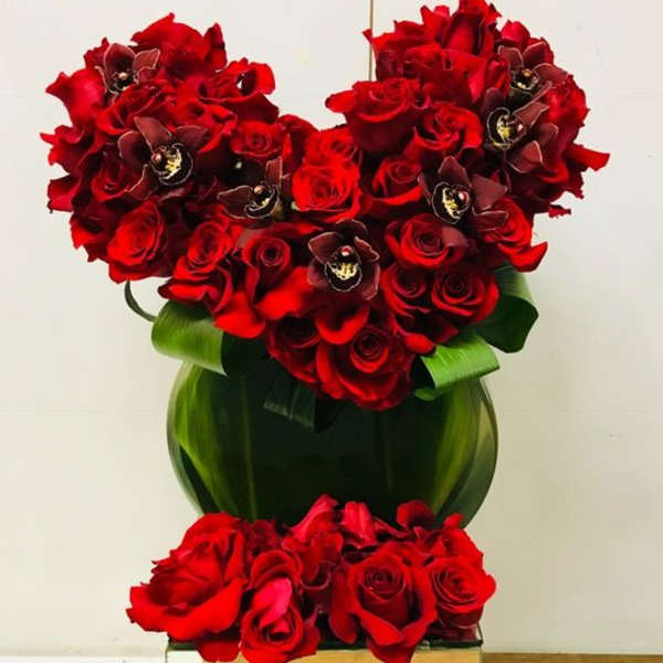 Heart-shaped red rose arrangement with a green ribbon wrap