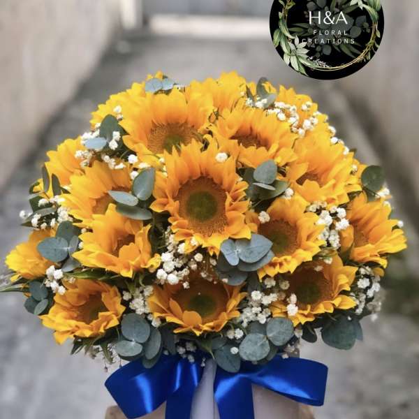 Bouquet of yellow sunflowers with blue ribbon in a white box