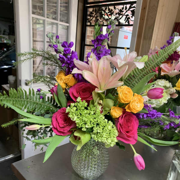 Mixed bouquet with pink roses, lilies, and purple flowers in a glass vase