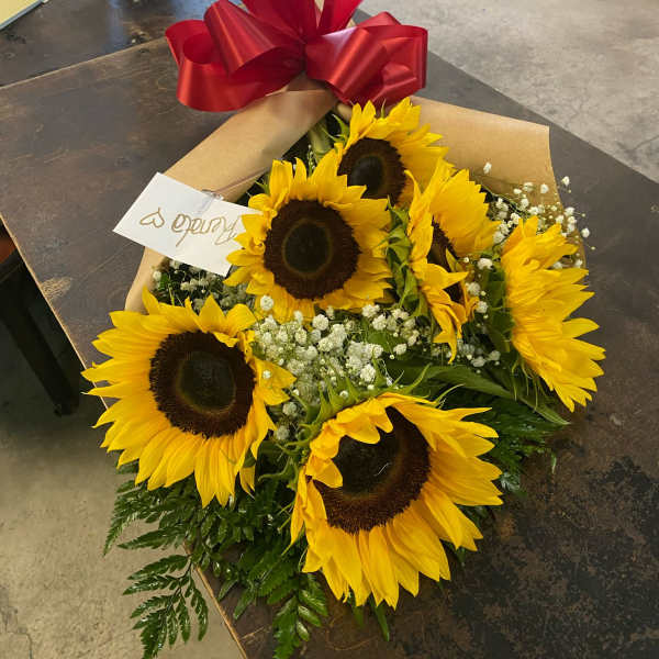 Bouquet of sunflowers wrapped in paper with a large red bow