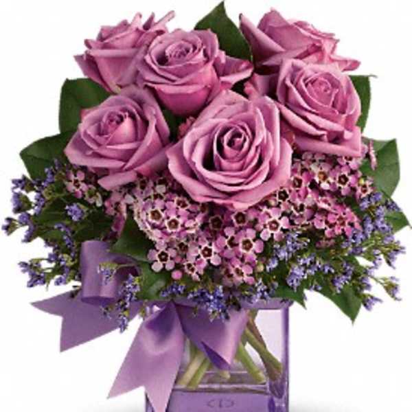 Bouquet of lavender roses with purple filler flowers in a glass vase