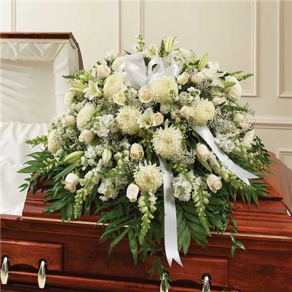 White funeral spray with lilies and roses on a casket
