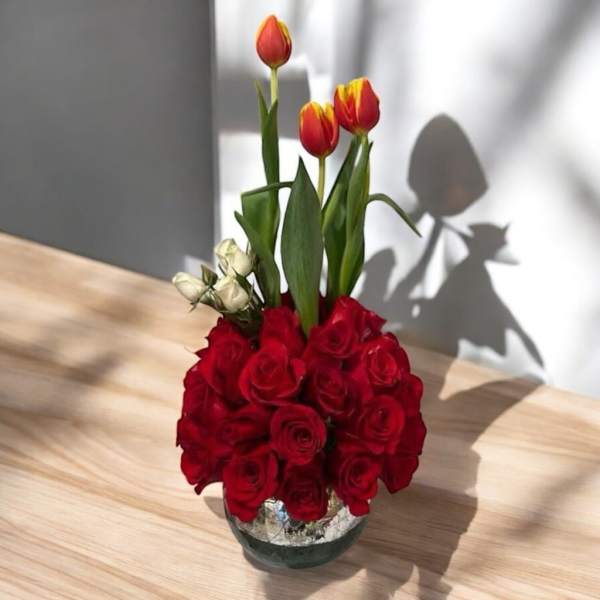 Red roses with red-yellow tulips in a glass vase