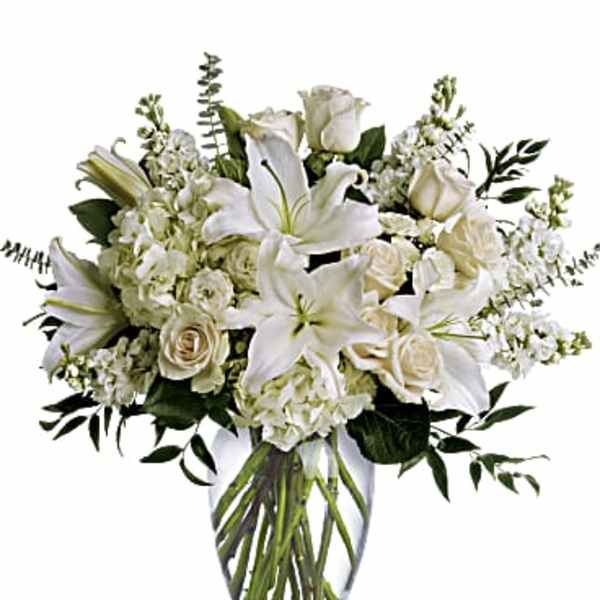 White lilies and roses arranged in a clear glass vase