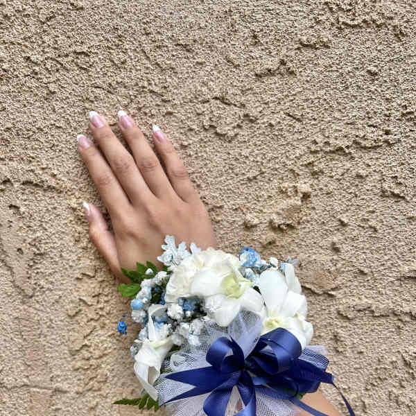 White floral wrist corsage with blue ribbon and tulle