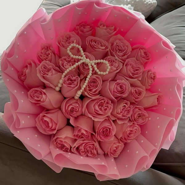 Bouquet of pink roses wrapped in pink paper with pearl accents