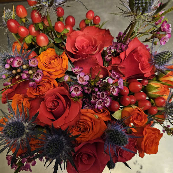 Bouquet of red and orange roses with purple thistle-like flowers