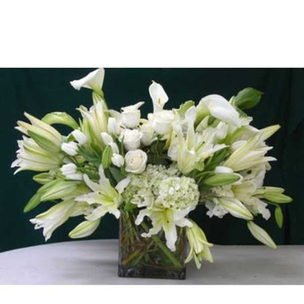 White lilies and roses arranged in a square glass vase