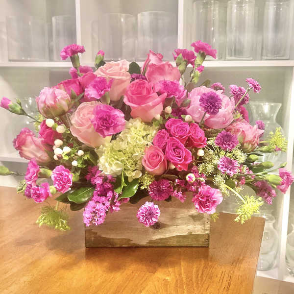 Pink and peach floral arrangement in a wooden box