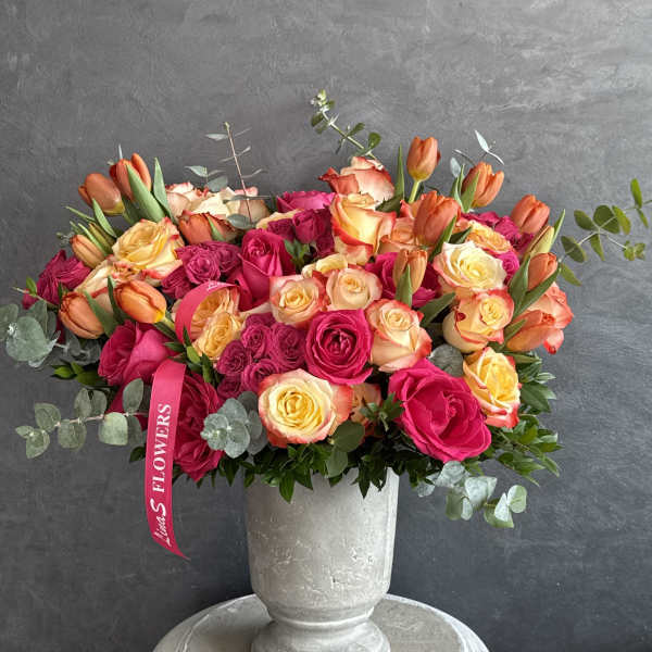 Bouquet of pink and peach roses in a gray urn vase