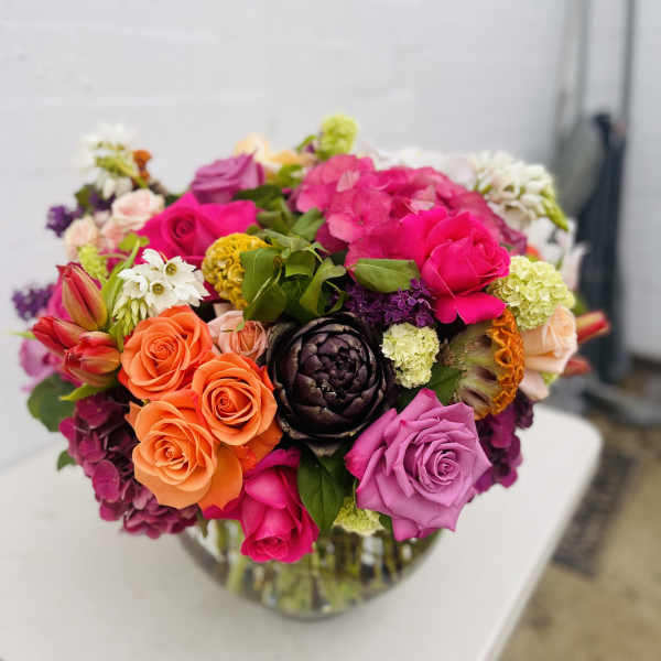 Bright mixed bouquet of roses and other flowers in a glass vase