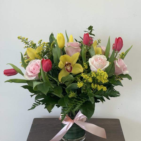 Pink and yellow tulips with roses in a glass vase