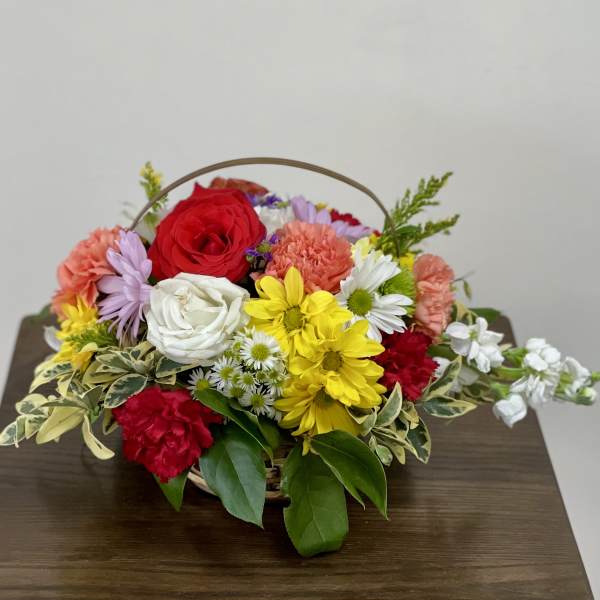 Basket arrangement of mixed roses, carnations, and daisies