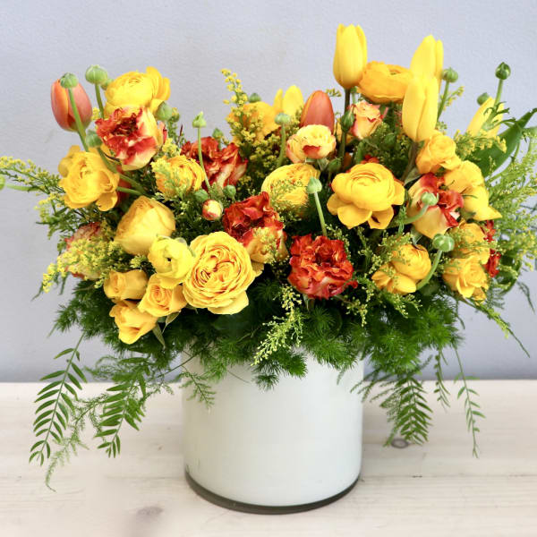 Yellow and red mixed flower arrangement in a white vase