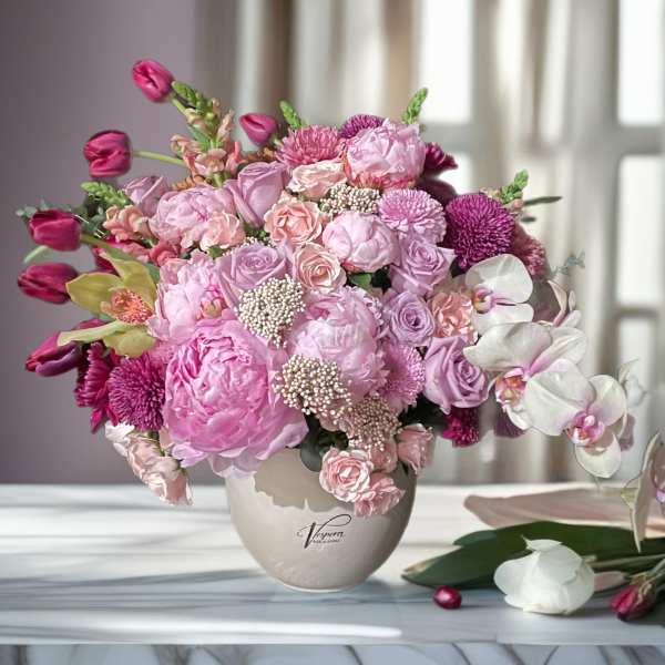 Pink and lavender flower arrangement in a beige vase