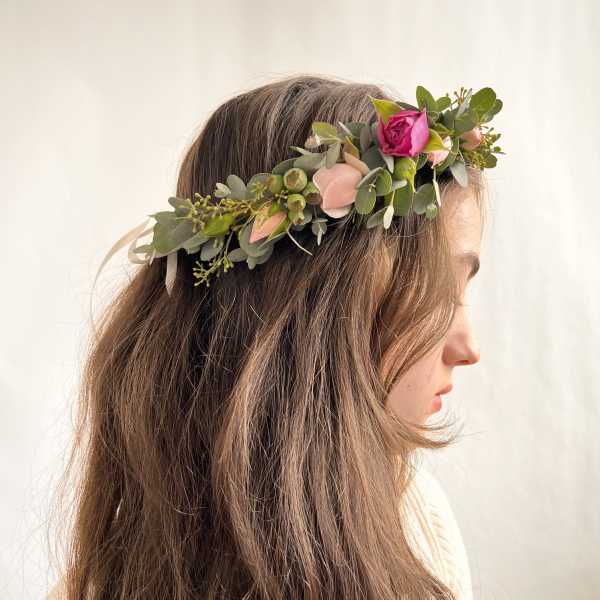 Floral crown with pink rose and peach buds worn in long brown hair in side profile view