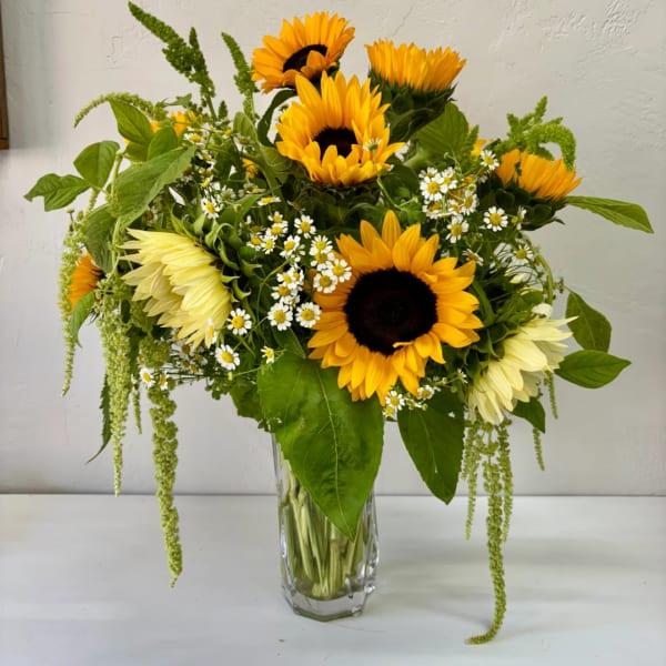 Sunflower bouquet with small white daisies in a clear glass vase
