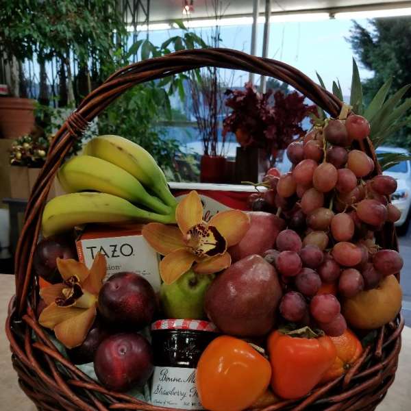 Fruit basket with grapes, bananas, citrus, and orchids in a wicker basket