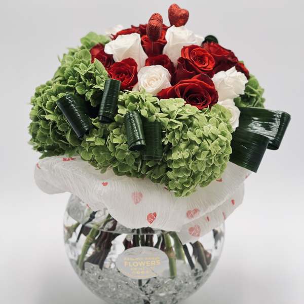 Bouquet of red and white roses with green hydrangeas in a glass vase