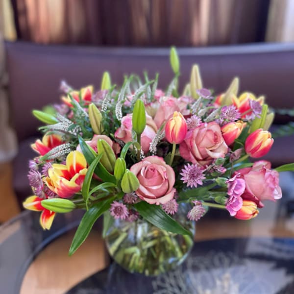 Bouquet of pink roses and multicolored tulips in a glass vase