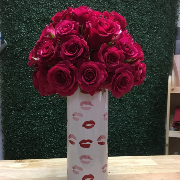 Bouquet of deep pink roses in a tall white vase with lip prints