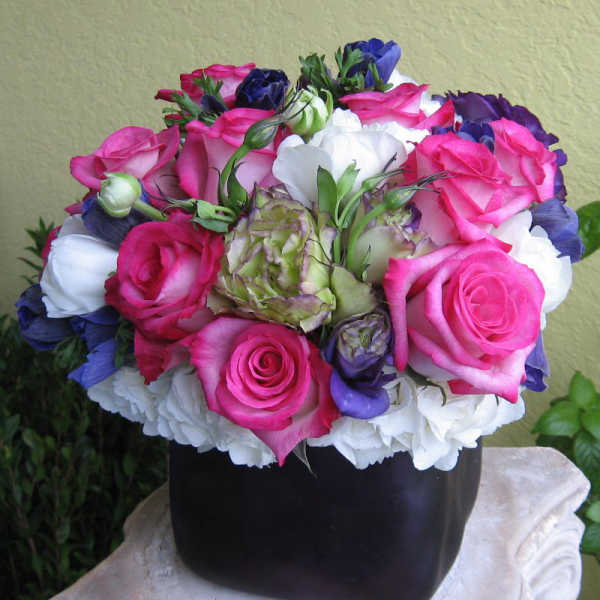 Bouquet of pink, white, and purple roses in a black vase