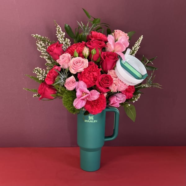 Pink and red rose bouquet arranged in a teal Stanley tumbler