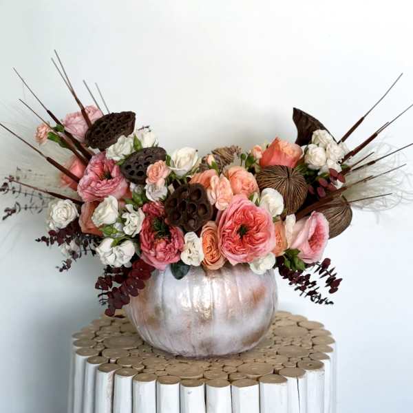 Pink and white floral arrangement in a metallic pumpkin vase