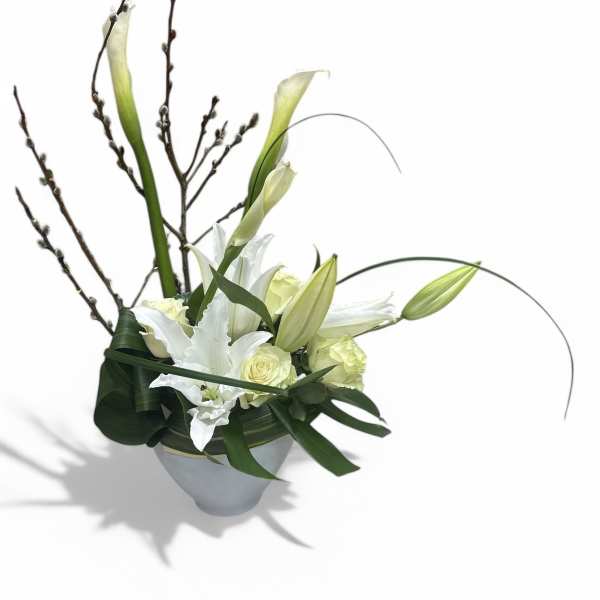 White calla lilies and roses in a white vase with tall branches