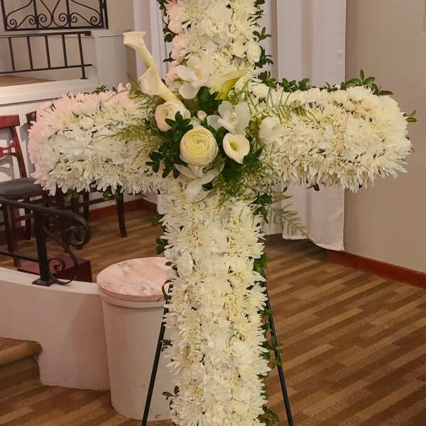 White floral cross on a stand with calla lilies and chrysanthemums