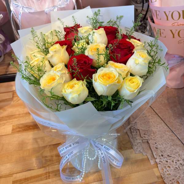 Bouquet of red and cream roses wrapped in white paper