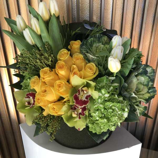 Yellow roses and white tulips in a round black container