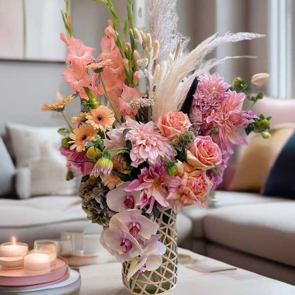 Pastel floral arrangement with orchids, roses, and dahlias in a lattice vase