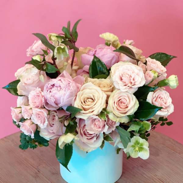 Pink and cream rose bouquet in a light blue vase