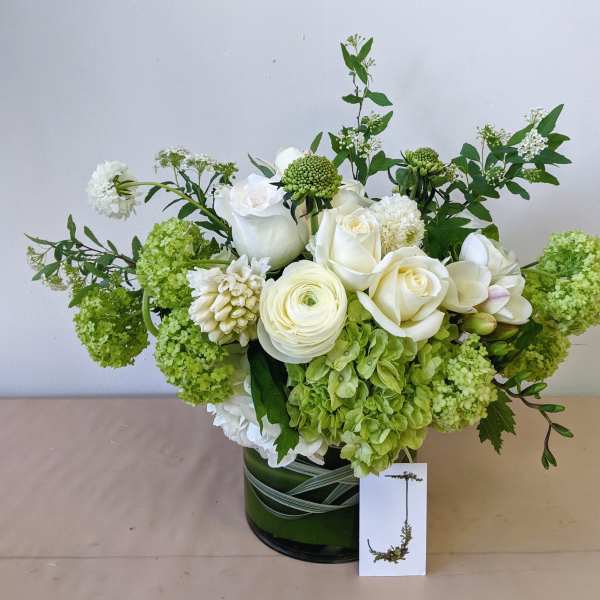 White and green floral arrangement in a dark glass vase