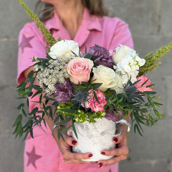 Handheld bouquet of pink, white, and purple flowers in a white vase