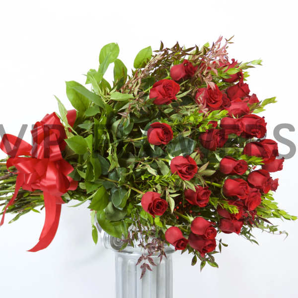 Bouquet of red roses with a red ribbon in a glass vase